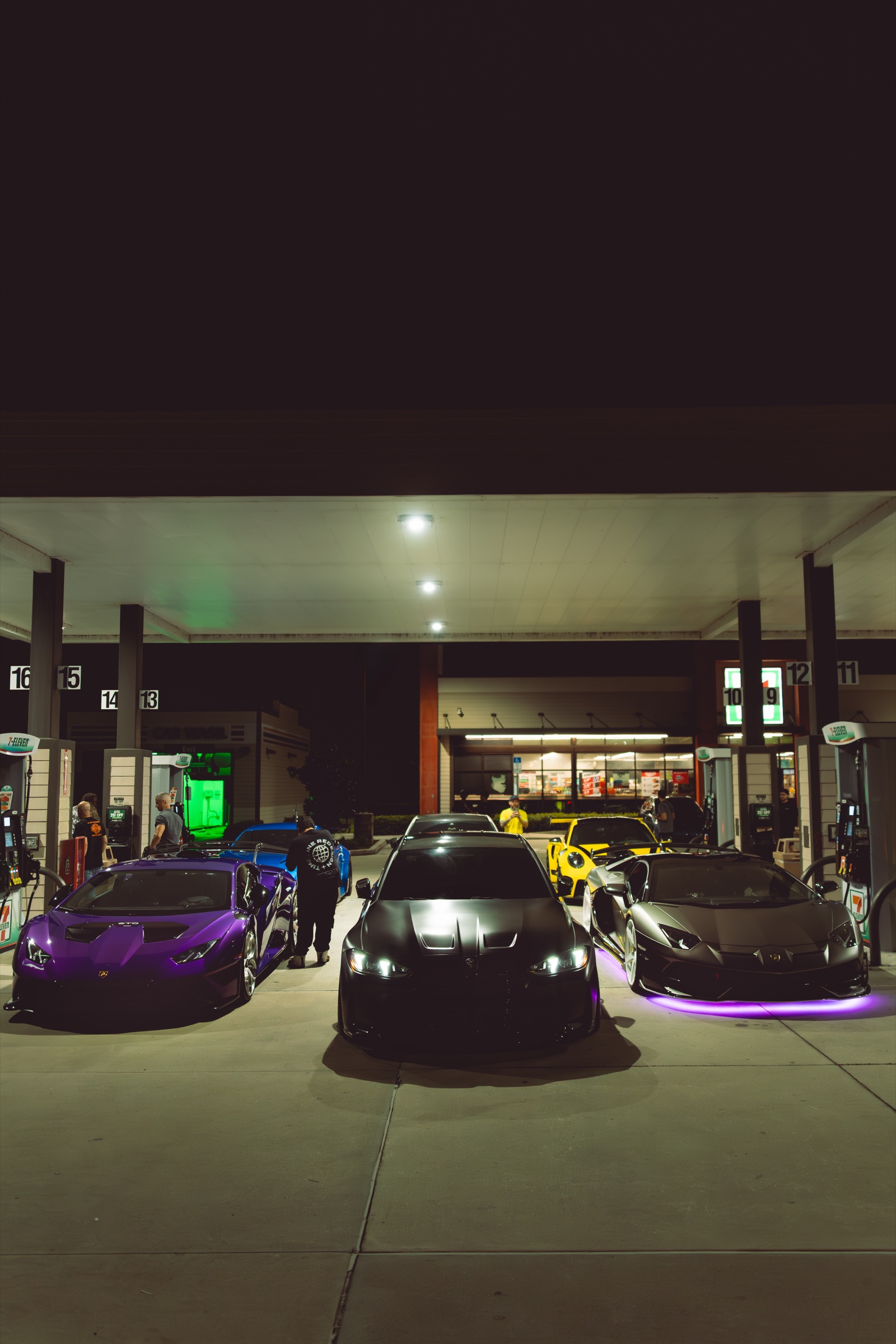 Cars with underglow at a gas station at night